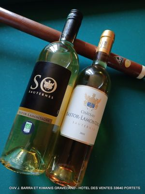 deux bouteilles de vin et un cigare posés sur une table de billard