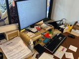 a desk with a computer, keyboard, and papers on it