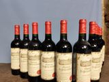 six bottles of red wine lined up on a wooden table