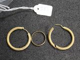 three pairs of gold hoop earrings on a black surface
