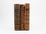 three old books sitting on top of each other on a white surface