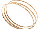 un gros plan sur une pile de bracelets rigides en or sur fond blanc