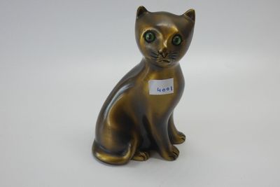 un petit chat en bronze avec une médaille attachée à son collier