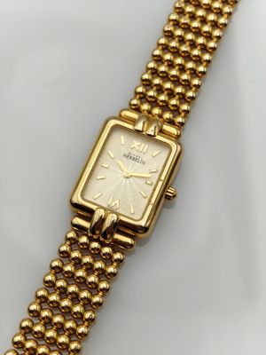 a close up of a gold watch on a white surface