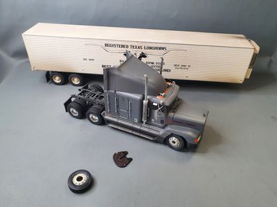 a toy semi truck with a semi trailer in the background