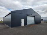 un grand bâtiment industriel doté d'une grande porte de garage, situé au milieu d'un parking