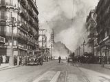 black and white photo of a city street with a train on the tracks
