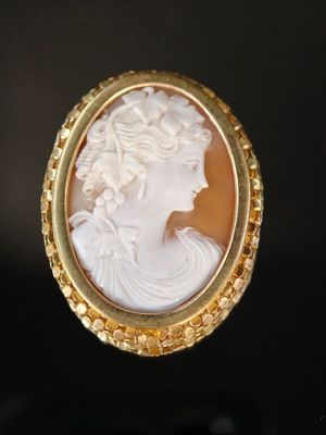 Une broche plaquée or représente le profil d'une femme.