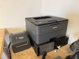 a black and gray printer sitting on top of a desk next to a telephone