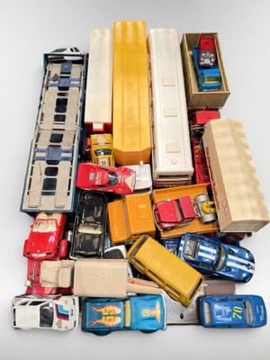 un tas de petites voitures et de camions miniatures posés sur une surface blanche