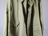 a green jacket hanging on a hanger on a gray wall