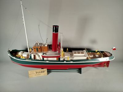 une maquette de bateau rouge et vert posée sur une table