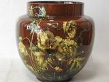 a brown vase with yellow flowers on it on a white surface
