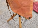 a brown leather chair on a wooden tripod