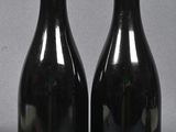 two bottles of red wine sitting next to each other on a table