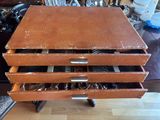 a brown wooden table with a drawer full of silverware