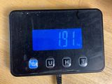 a digital clock that is on the table next to a cup of coffee