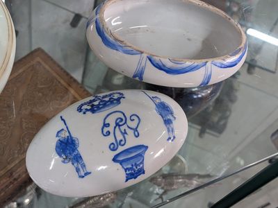 three blue and white porcelain objects on display in a glass case