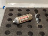 a tube of paint sitting on the floor next to a piece of paper