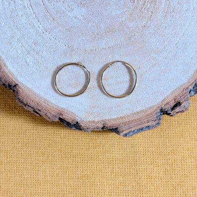 pair of silver wedding rings sitting on top of a piece of wood