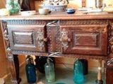a wooden cabinet with glass bottles on the floor