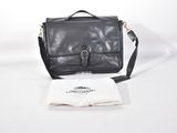 Le petit sac noir est posé sur la table, à côté d'une nappe blanche.