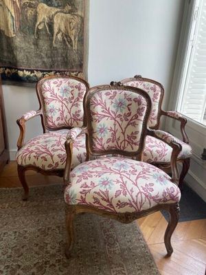 trois chaises dans une pièce avec un tapis et un tableau accroché au mur