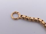 a close up of a gold bracelet with a clasp on a white surface