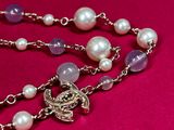 purple and white pearl rosary necklace with a silver cross on a pink background