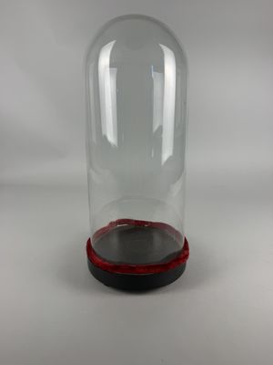 clear glass bell jar with red base on a white background