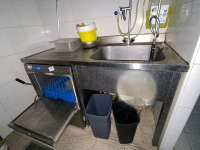 a kitchen with a sink, trash can, and trash can in it