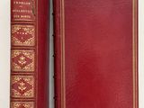 an old red book with gold trim sitting on top of a white surface
