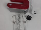 a red hand blender sitting on a white table
