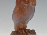 an owl statue sitting on a rock on a white surface