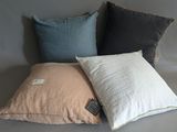 three pillows on a grey couch with a tag on them