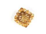 une image représentant une broche plaquée or ornée de fleurs et de feuilles