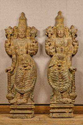 une paire de statues en bois sculptées représentant des divinités hindoues, posées sur un plancher en bois