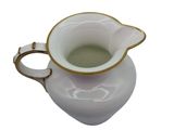a white pitcher with a gold rim and a handle