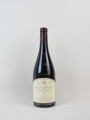 une bouteille de vin posée sur une table à côté d'un mur blanc