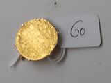 une pièce d'or posée sur une table blanche, avec une étiquette indiquant son prix