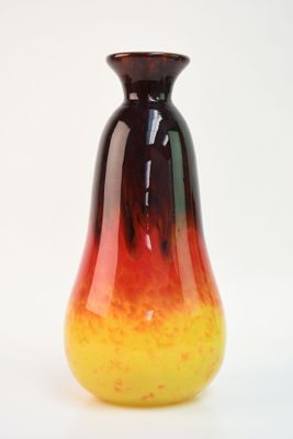 un vase rouge et jaune posé sur une surface blanche