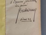 un vieux livre sur lequel on peut lire une inscription manuscrite, posé sur une table