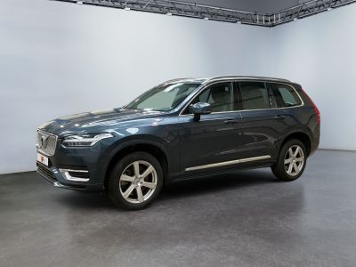 a grey volvo suv parked in a showroom with a white wall