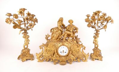 une horloge en or posée sur une table, à côté de trois autres horloges