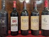 six bouteilles de vin sont alignées sur une nappe rouge