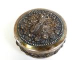 a silver box with a bird on it on a white surface
