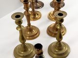 six brass candlesticks on a white table with a white background