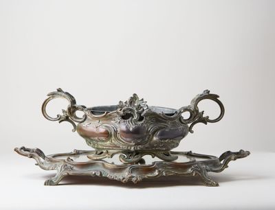 a silver bowl on a stand on a white surface