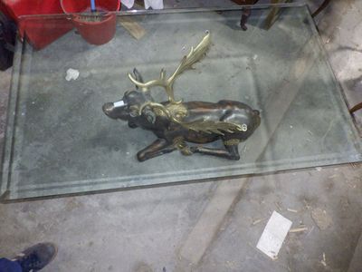 une table en verre sur laquelle se trouve un cerf en bronze