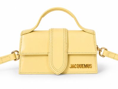 a small yellow purse with a gold logo on the front